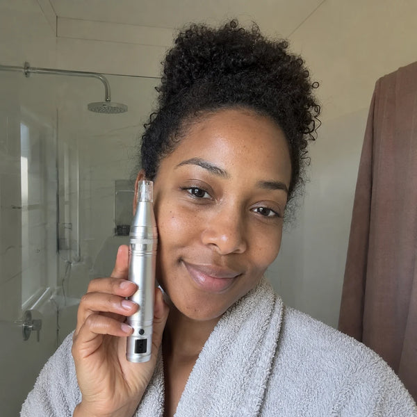 Femme aux cheveux bouclés qui utilise le Feevra Microneedling Pen sur sa joue