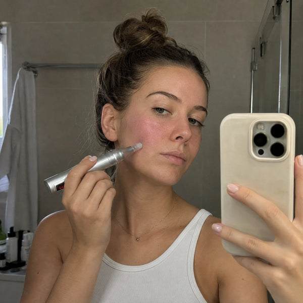 Femme qui prend un selfie dans le miroir en utilisant le Feevra Microneedling Pen